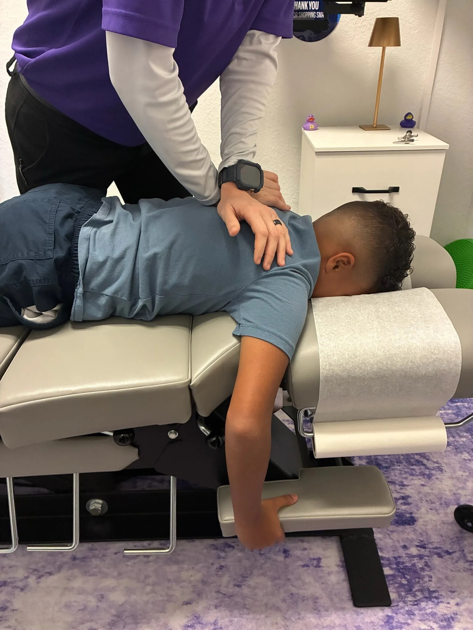 Chiropractor performing an adjustment on a young patient lying on a treatment table