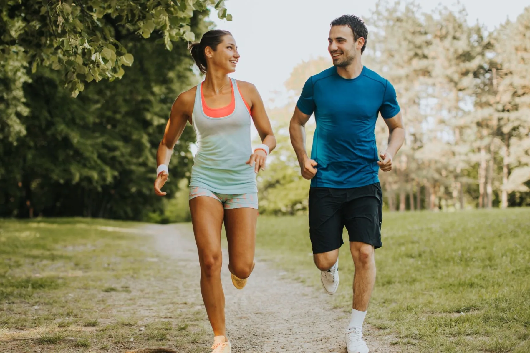 Man and woman jogging together on a tree-lined trail