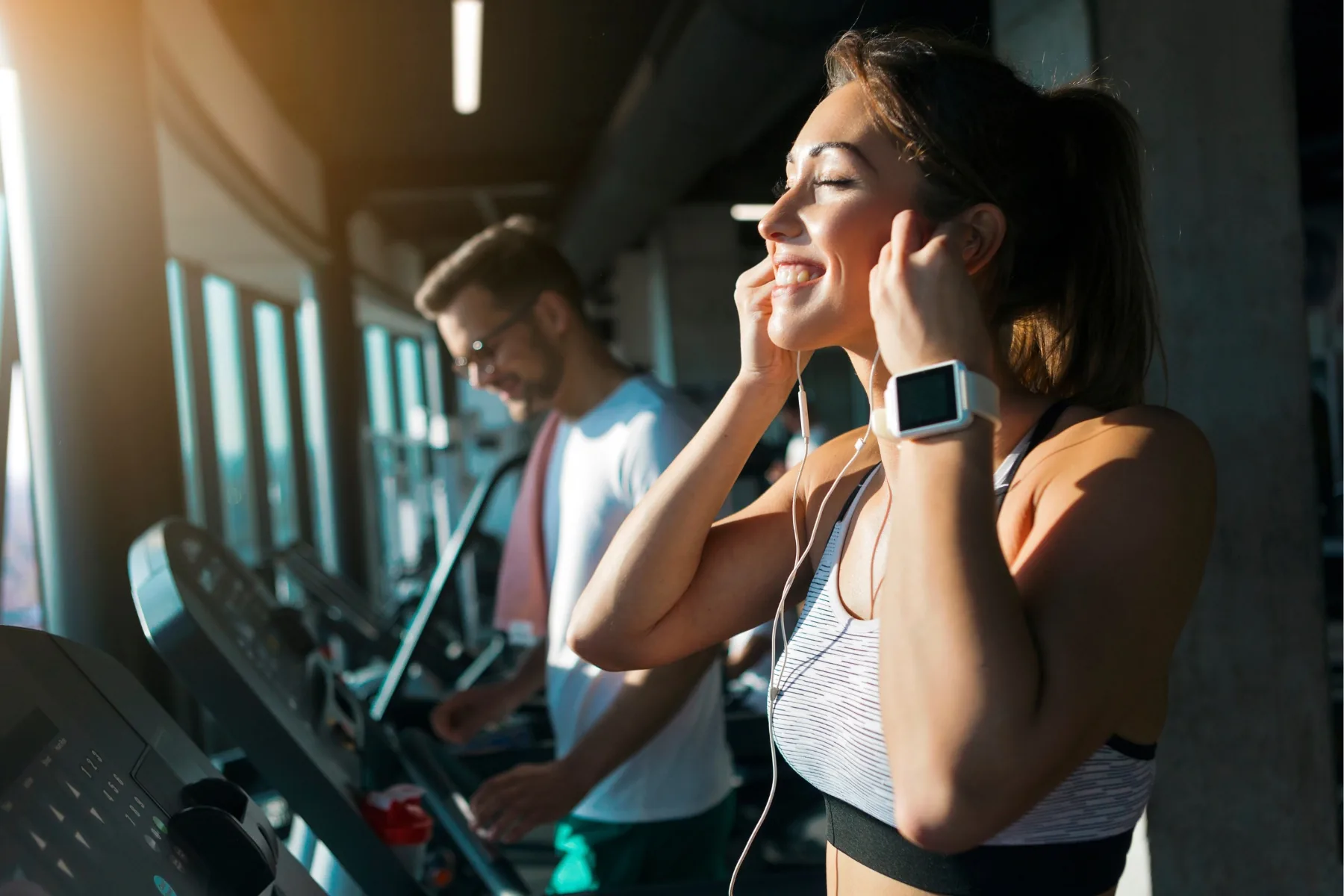Woman with headphones exercising on a treadmill in a gym